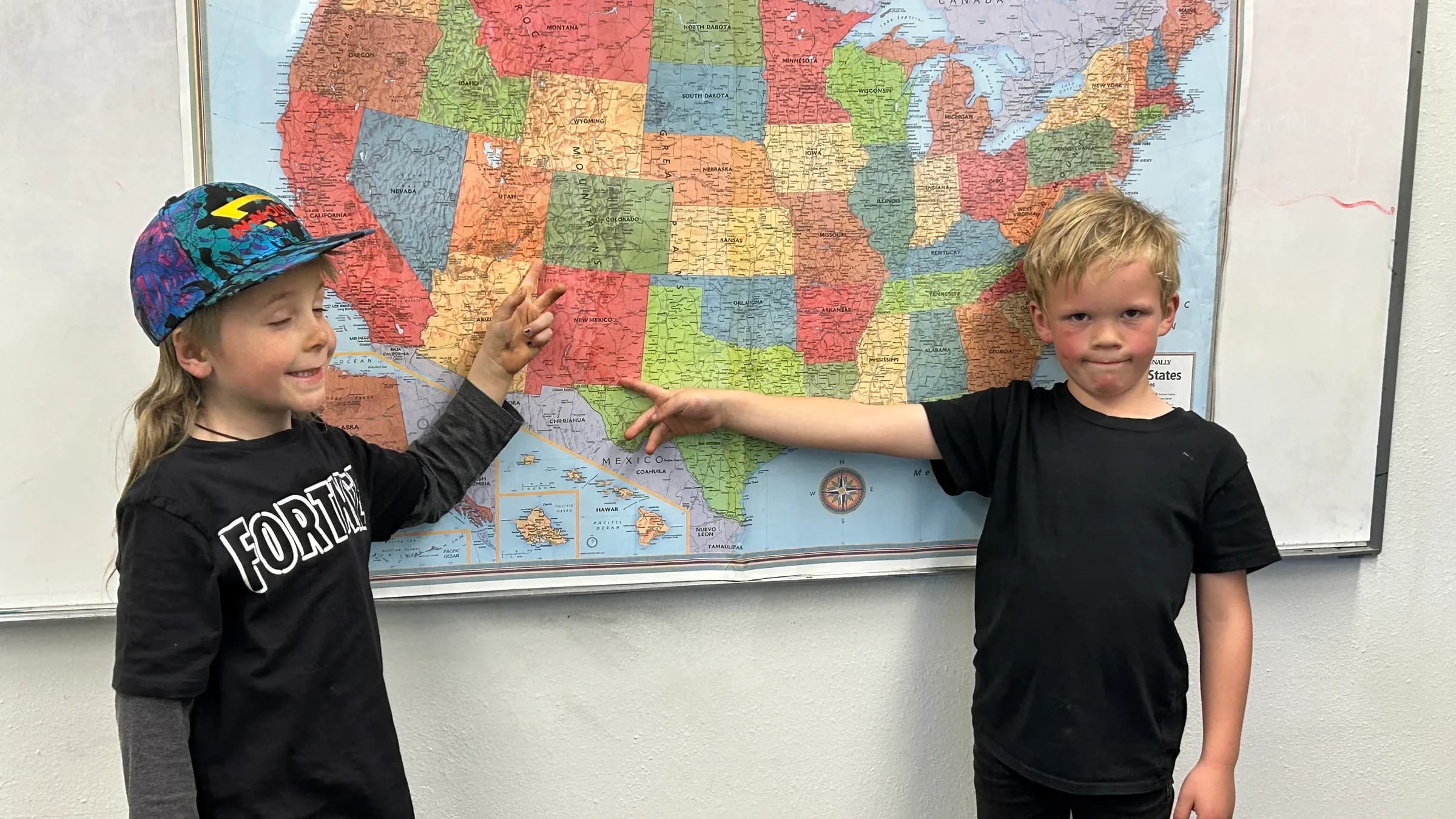 Two SPRUCE students point to the Four Corners on a classroom map of the United States.